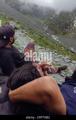 Juli 25.2024, Himachal Pradesh, Indien. Anhänger, die während des Mani Mahesh Kailash Yatra im Chamba Valley, hoch, die majestätischen Berge bewundern und ausruhen Stockfoto