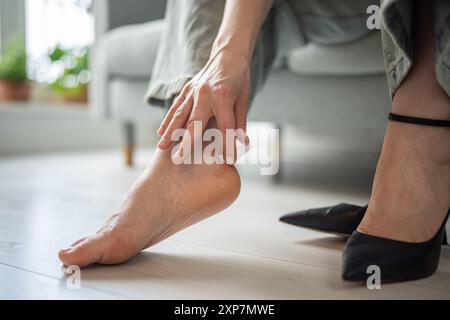 Weibliche Finger legen Gips auf den Kallus, die Frau leistet erste Hilfe bei Schmerzen am Knöchel durch das Tragen neuer Schuhe. Stockfoto