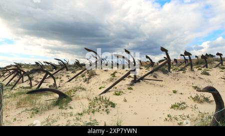 Rostige Anker liegen an einem Sandstrand unter bewölktem Himmel Praia do Barril Strand Algarve Portugal. Stockfoto