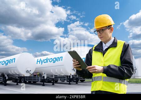 Mann mit digitalem Tablet auf einem Hintergrund eines Wasserstofftankanhängers. Stockfoto