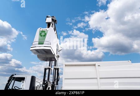 Müllwagen hebt den Straßenbehälter für recycelbaren Abfall an. Stockfoto