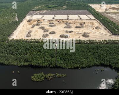 Sandabbau. Maschinen und Lkw, die auf Sandminen arbeiten. Bergbau Steinbruch Tagebau Aushub Sandmine. Drohnenansicht einer Sandmine im Wald. Stockfoto