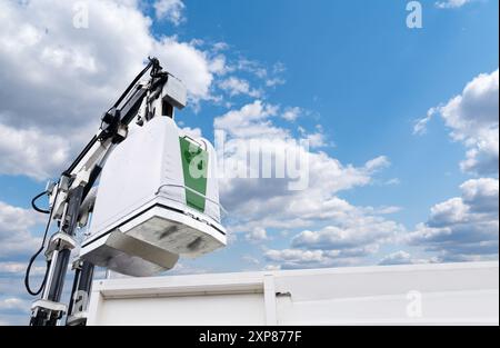 Müllwagen hebt den Straßenbehälter für recycelbaren Abfall an. Stockfoto