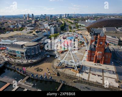 CARDIFF, WALES - 29. JULI 2024: Aus der Vogelperspektive auf das Pierhead-Gebäude der Cardiff Bay, das Rad und die Sommerattraktionen des Messegeländes Stockfoto