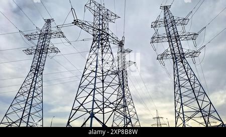 Mehrere Hochspannungsleitungen gegen einen dramatisch bewölkten Himmel. Stockfoto