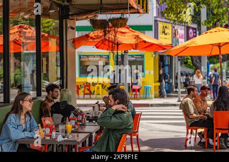 Los Angeles, CA, USA-25. Mai 2024: Menschen, die an einem sonnigen Sommertag in einem Restaurant im Freien in einem lebhaften Wohnviertel essen. Stockfoto