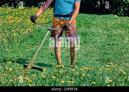 Durch die Verwendung von Unkrautbrechern werden die Beine des Gärtners mit gehacktem Gras bedeckt. Stockfoto