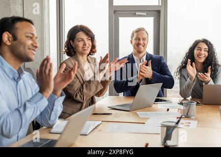 Vielseitiges Team applaudiert bei erfolgreicher Besprechung in einem modernen Büro Stockfoto