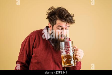 Freizeit und Bierzeit. Betrunkener bärtiger Mann, der frisch gebrautes Bier probiert. Oktoberfest. Brauer mit einem Glas Craft-Bier. Deutsche Traditionen. Alkohol Stockfoto