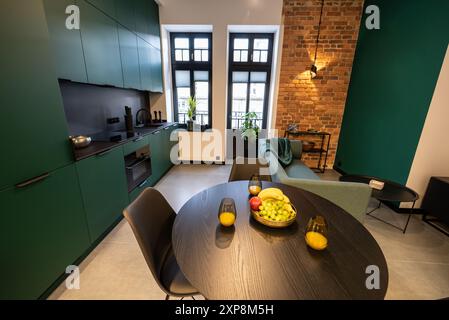 Stilvolle Küche, die nahtlos mit einem gemütlichen Wohnzimmer verbunden ist. Moderne Küche, verbunden mit dem Wohnzimmer in einem kleinen Apartment. Modern eingerichtete Küche Stockfoto