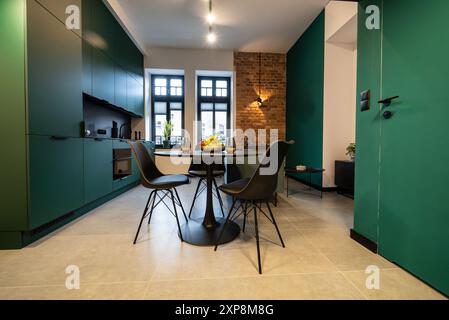 Stilvolle Küche, die nahtlos mit einem gemütlichen Wohnzimmer verbunden ist. Moderne Küche, verbunden mit dem Wohnzimmer in einem kleinen Apartment. Modern eingerichtete Küche Stockfoto