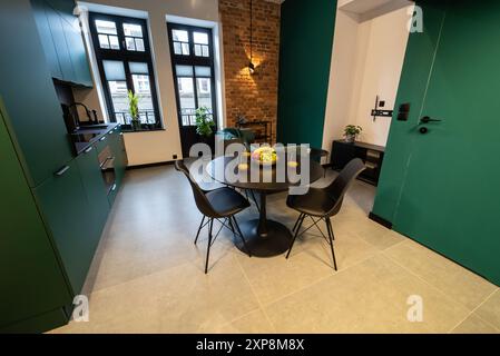 Stilvolle Küche, die nahtlos mit einem gemütlichen Wohnzimmer verbunden ist. Moderne Küche, verbunden mit dem Wohnzimmer in einem kleinen Apartment. Modern eingerichtete Küche Stockfoto