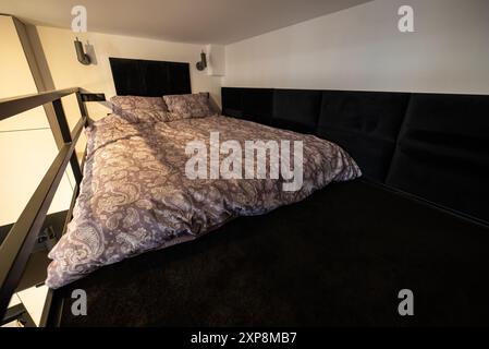 Modernes Studio-Apartment mit einem Schlafzimmer im Zwischengeschoss. Das Innere eines Hotelschlafzimmers mit Bett und Kissen. Kleines und modernes Apartment mit Zwischengeschoss Stockfoto