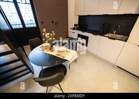 Stilvolle Küche, die nahtlos mit einem gemütlichen Wohnzimmer verbunden ist. Moderne Küche, verbunden mit dem Wohnzimmer in einem kleinen Apartment. Modern eingerichtete Küche Stockfoto