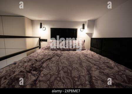 Modernes Studio-Apartment mit einem Schlafzimmer im Zwischengeschoss. Das Innere eines Hotelschlafzimmers mit Bett und Kissen. Kleines und modernes Apartment mit Zwischengeschoss Stockfoto