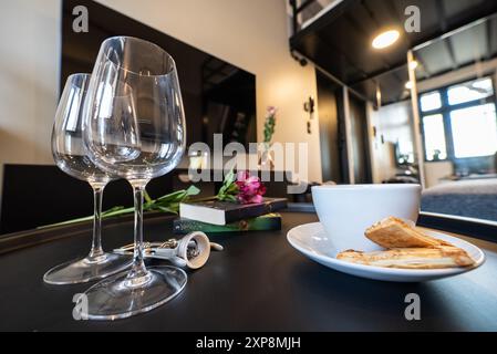 Weinglas und Buch auf dem Tisch im luxuriösen Hotelzimmer. Modern eingerichtete Küche und ein Esszimmer. Moderne Küche, die mit dem Wohnzimmer verbunden ist Stockfoto