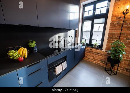 Modern eingerichtete Küche mit Haushaltsgeräten und Esszimmer. Innenraum einer modernen Küche in einem neuen Haus. Esstisch und Stühle in stilvoller Ausführung Stockfoto