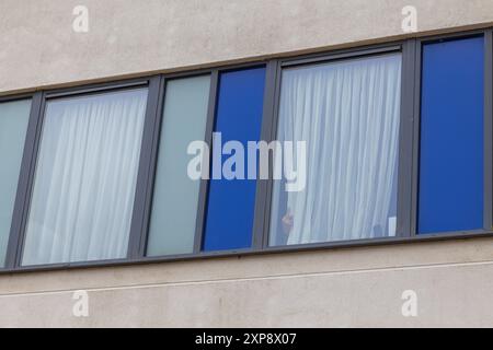 Rotherham, Großbritannien. AUGUST 2024. Die im Hotel untergebrachten Personen blicken aus den Fenstern auf die Menschenmenge, während Hunderte von Polizisten und Demonstranten vor einem Holiday Inn Express am Manvers Way, Rotherham, aufeinander treffen. Die Demonstranten des rechten Flügels, die von Sir Kier Starmer als „Gangster“ beschrieben wurden, zündeten Eigentum an, zerschlugen Glas und kämpften mehrere Stunden mit der Polizei. Mehrere Verhaftungen und Verletzungen von Aufständischen und Polizei. Credit Milo Chandler/Alamy Live News Stockfoto