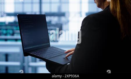 Techniker, der die Überprüfung durchführt und Daten auf Laptop mit den erforderlichen Servernhubs-Fehlerbehebungen eingibt. Nahaufnahme eines Mitarbeiters, der im Rechenzentrum arbeitet und eine erweiterte Speicherinfrastruktur zur Unterstützung von IT-Workloads bietet, Kamera A Stockfoto