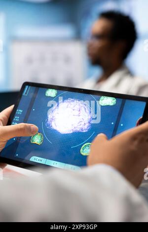 In einem Behandlungszentrum analysiert der Arzt die mrt-Daten des Gehirns auf einem Tablet und untersucht die Tomographieergebnisse. Das Team der Neurologie konzentriert sich auf Röntgenaufnahmen und Diagnostik zur Prävention von Krankheiten. Nahaufnahme. Stockfoto