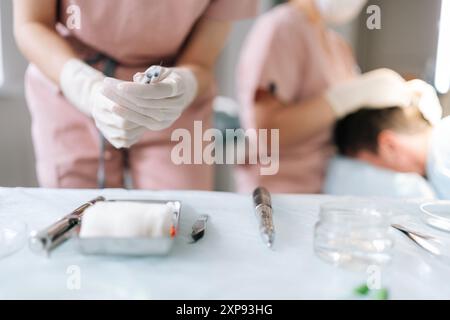 Nahaufnahme Handschuhe der nicht erkennbaren Krankenschwester Assistenten entfernen die Kappe von der Nadel der Spritze, Vorbereitung auf die Operation im Krankenhaus. Stockfoto