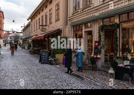 Göteborg, Schweden, 4. Januar 2024. Leute laufen auf einer schneebedeckten Kopfsteinpflasterstraße in Haga Stockfoto