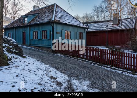 Traditionelles schwedisches blaues Holzhaus in einer verschneiten Straße im Gathenhielm Cultural Reserve, Göteborg Stockfoto
