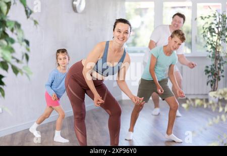 Glückliche Frau mittleren Alters, die mit ihren Familienmitgliedern Tanzbewegungen praktiziert Stockfoto