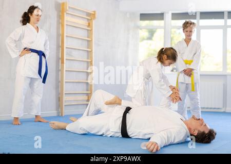 Judo- oder Jiu Jitsu-Kurse - Familie mit zwei Kindern, die das Greifen und Werfen auf Sportmatten üben Stockfoto