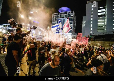 Demonstranten marschieren mit der israelischen Flagge, Spruchbanner und einem Rauchfackel während der Demonstration. Während Israel nach den Ermordungen des Hamas-Führers Ismail Haniyah in Teheran und des hochrangigen Hezbollah-Kommandeurs Fuad Shukr in Beirut auf mögliche Vergeltungsmaßnahmen seitens Iran und der Hisbollah vorbereitet ist, Familien israelischer Geiseln, die von der Hamas in Gaza festgehalten werden, begehen den 300. Tag seit dem Massaker vom 7. Oktober und der Entführung ihrer Angehörigen. Die Familien fordern eine Freilassung von Geiseln mit 115 Geiseln, von denen einige tot und andere lebendig sind, die noch immer in Gaza festgehalten werden. Stockfoto