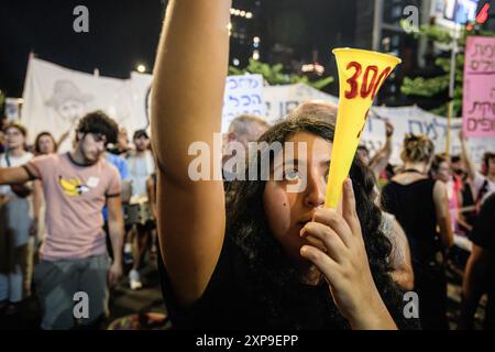 Tel Aviv, Israel. August 2024. Ein Protestor sprengt während der Demonstration eine Vuvuzela. Während Israel nach den Ermordungen des Hamas-Führers Ismail Haniyah in Teheran und des hochrangigen Hezbollah-Kommandeurs Fuad Shukr in Beirut auf mögliche Vergeltungsmaßnahmen seitens Iran und der Hisbollah vorbereitet ist, Familien israelischer Geiseln, die von der Hamas in Gaza festgehalten werden, begehen den 300. Tag seit dem Massaker vom 7. Oktober und der Entführung ihrer Angehörigen. Die Familien fordern eine Freilassung von Geiseln mit 115 Geiseln, von denen einige tot und andere lebendig sind, die noch immer in Gaza festgehalten werden. Quelle: SOPA Images Limited/Alamy Live News Stockfoto