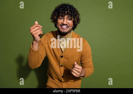 Foto-Porträt des attraktiven jungen Mannes, der tanzt, haben Spaß gekleidete stilvolle braune Kleidung isoliert auf khakifarbenem Hintergrund Stockfoto