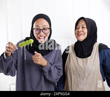 Indonesische muslimische Mutter und Tochter glücklich, Frucht Shine Muscat mit Zucker oder Tanghulu in der Küche zu machen Stockfoto