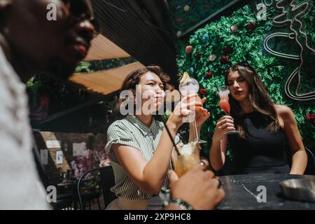 Multikulturelle Geschäftsleute genießen Drinks und feiern Erfolge im Freien in einer lebhaften Umgebung Stockfoto