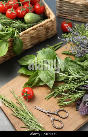 Verschiedene aromatische Kräuter, Gemüse und Scheren auf grauem Tisch, Nahaufnahme Stockfoto