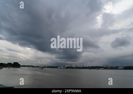 Schwere Monsunwolken schweben über dem Ganges, mit der Skyline von Kalkutta im Hintergrund. Kalkutta, Westbengalen, Indien. Stockfoto