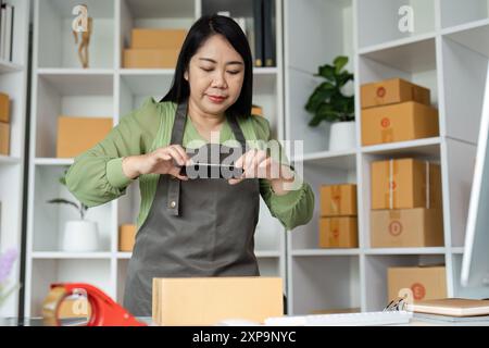 Senior Entrepreneur, der ein Unternehmen gründet – Woman Packaging Products im modernen Home Office Stockfoto