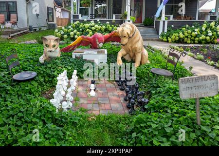 Eine anthropomorphe Szene, in der Tiere dargestellt werden – eine Katze, ein Papagei und ein Hund, der im Freien Schach spielt, im Süden von Minneapolis, Minnesota. Stockfoto