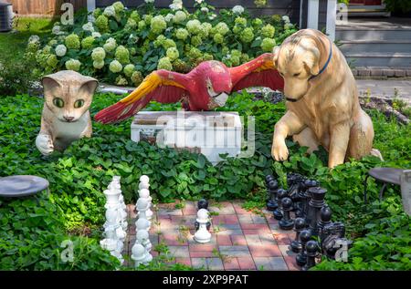 Eine anthropomorphe Szene, in der Tiere dargestellt werden – eine Katze, ein Papagei und ein Hund, der im Freien Schach spielt, im Süden von Minneapolis, Minnesota. Stockfoto