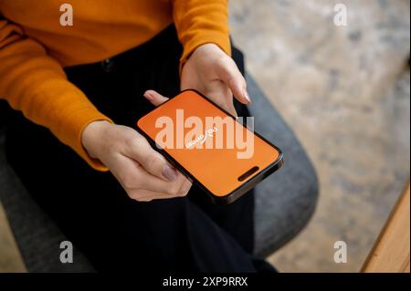 Chiang mai, Thailand - 1. August 2024: Ein Nahaufnahme einer Frau, die drinnen sitzt und die Payoneer-App auf ihrem iPhone nutzt. Das Payoneer App-Logo auf einem s Stockfoto