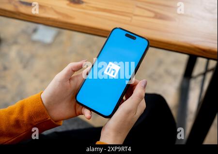 Chiang mai, Thailand - 1. August 2024: Ein Nahaufnahme einer Frau, die drinnen sitzt und die LinkedIn App auf ihrem iPhone nutzt. Das LinkedIn App-Logo auf einem s Stockfoto