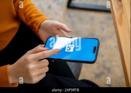 Chiang mai, Thailand - 1. August 2024: Ein Nahaufnahme einer Frau, die drinnen sitzt und die LinkedIn App auf ihrem iPhone nutzt. Das LinkedIn App-Logo auf einem s Stockfoto