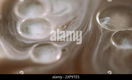 Ölflüssigkeit. Glitzernebel. Defokussierte weiße Bronze beige Farbe transparente sprudelnde Blasen schwimmende Tinte Wasserstrom abstrakte Kunst Hintergrund. Stockfoto