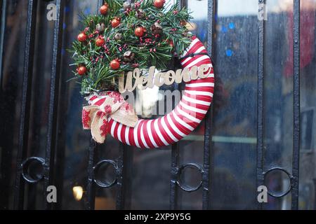 Ein weihnachtlicher Willkommenskranz wird elegant an einem bezaubernden Eingang zur Schwarzen Tür präsentiert Stockfoto