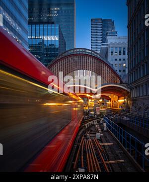 Eine pulsierende rote U-Bahn-Linie in London fährt nachts durch die geschäftige Stadt Stockfoto