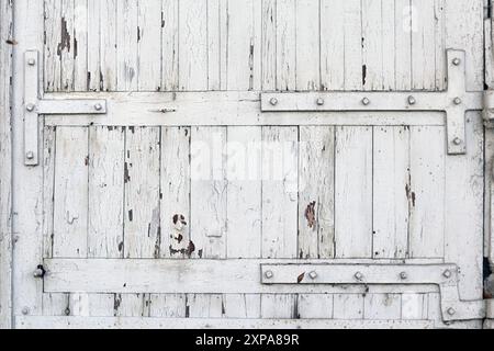 Weiß lackierte Holztür mit Metallscharnieren. Rustikaler und verwitterter Texturhintergrund. Stockfoto