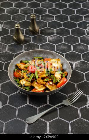 Gebratene Ravioli mit Hähnchenfleisch, serviert mit gebratenen grünen Bohnen, Tomaten und Pilzen Stockfoto