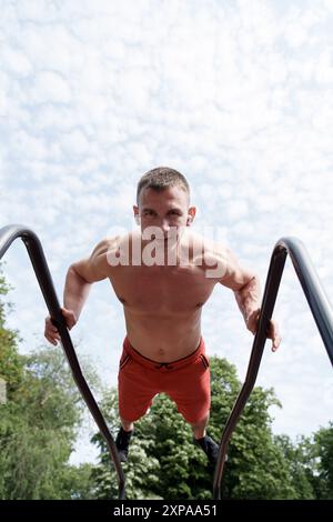 Ein Mann, der im Park Einbrüche an parallelen Leisten durchführt Stockfoto