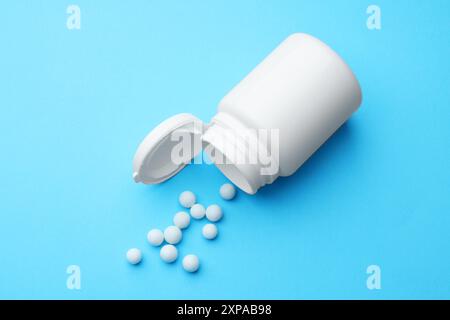 Homöopathie. Umgedrehte Plastikflasche und Pillen auf hellblauem Hintergrund Stockfoto