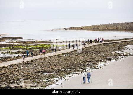 Touristen wandern auf dem Granitdamm von Marazion zur Tidal Island St. Michaels's Mount, Marazion, Cornwall, England Stockfoto